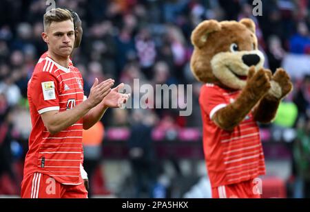 Munich, Allemagne. 11th mars 2023. Football, Bundesliga, FC Bayern Munich - FC Augsburg, Matchday 24 à Allianz Arena. Joshua Kimmich de Munich remercie les fans après le match. À côté de lui va la mascotte Berni l'ours. Crédit : Sven Hoppe/dpa - REMARQUE IMPORTANTE : Conformément aux exigences de la DFL Deutsche Fußball Liga et de la DFB Deutscher Fußball-Bund, il est interdit d'utiliser ou d'avoir utilisé des photos prises dans le stade et/ou du match sous forme de séquences et/ou de séries de photos de type vidéo./dpa/Alay Live News Banque D'Images