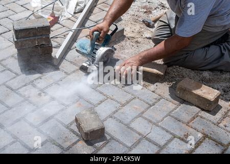 Ouvrier de construction brésilien utilisant une scie à béton pour couper le bloc. Banque D'Images