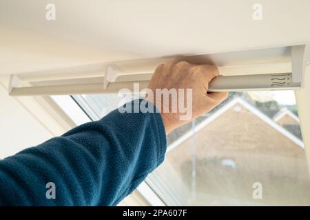 Un petit foyer d'un propriétaire a vu saisir la barre sur une nouvelle fenêtre Skylight installée, cherchant à l'ouvrir partiellement pour la ventilation. Banque D'Images