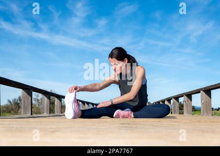 Coureur sportif assis faisant un exercice d'échauffement d'étirement de jambe. Banque D'Images