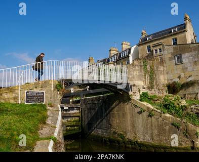 Homme traversant une passerelle en fonte aux écluses de Widcombe sur le canal Kennet et Avon à Bath Somerset, Royaume-Uni Banque D'Images