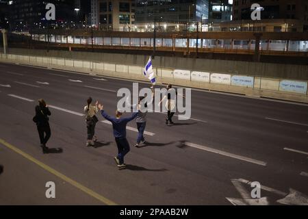 Tel Aviv, Israël. 11th mars 2023. Des manifestants israéliens bloquent la route au cours d'une manifestation contre la réforme du système juridique prévue par le gouvernement. Crédit : Ilia Yefimovich/dpa/Alay Live News Banque D'Images