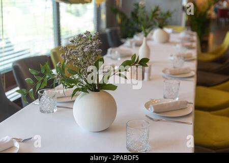 Fleurs séchées dans un vase blanc rond comme décoration de table pour une fête de mariage. Couverts et verres. Banque D'Images
