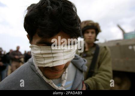 An Israeli Soldier Escorts A Blindfolded Palestinian Detainee Who Was ...