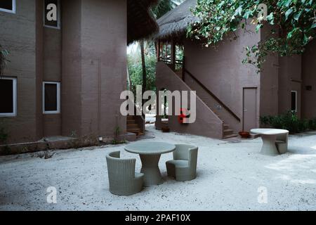 Une villa dans des tons ocre pour le tourisme dispose de meubles de plein air élégants et confortables, y compris une table basse et des chaises en rotin, fournissant un p Banque D'Images