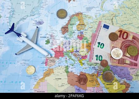 Paris, France - 19 février 2019: Composition d'une carte du monde centrée en Europe avec des billets et pièces en euros ainsi qu'un avion de jouet. Banque D'Images