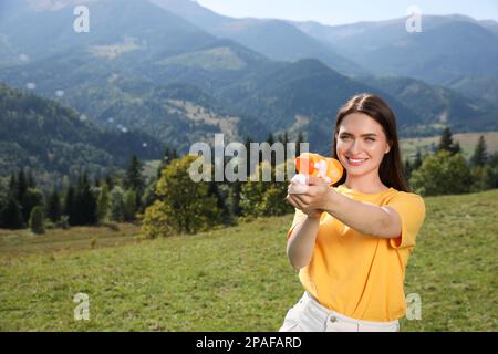 Bonne femme avec un pistolet à eau s'amusant dans les montagnes par beau temps Banque D'Images