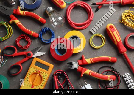 Composition de pose à plat avec outils et accessoires d'électricien sur fond gris Banque D'Images