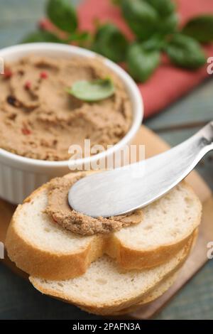 Étaler un délicieux pâté de viande sur une tranche de pain et un couteau sur la table, en gros plan Banque D'Images