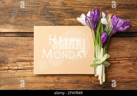 Belles fleurs de ccrocus de printemps et carte avec phrase Happy Monday sur table en bois, plat Banque D'Images