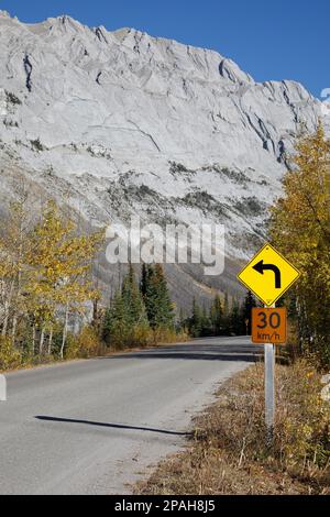 Signalisation routière avec limite de vitesse de 30 km/h et avertissement pour la courbe à venir sur une route à travers les montagnes dans le parc national Jasper, Canada. Banque D'Images