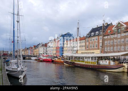 Vue aérienne sur le canal de Nyhavn avec bateau flottant qui regorge de touristes et d'arrière-plan de maisons de ville emblématiques colorées le long du front de mer pendant le nuage Banque D'Images