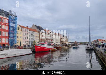 Vue aérienne sur le canal de Nyhavn avec bateau flottant qui regorge de touristes et d'arrière-plan de maisons de ville emblématiques colorées le long du front de mer pendant le nuage Banque D'Images