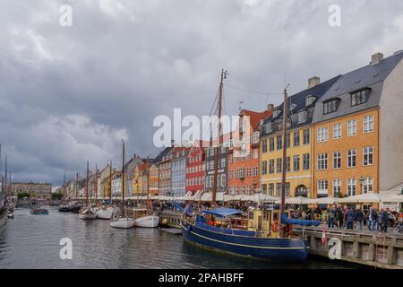 Vue aérienne sur le canal de Nyhavn avec bateau flottant qui regorge de touristes et d'arrière-plan de maisons de ville emblématiques colorées le long du front de mer pendant le nuage Banque D'Images