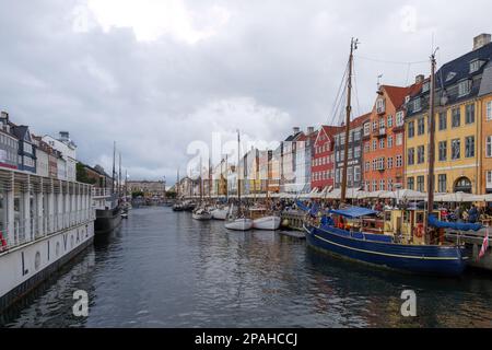 Vue aérienne sur le canal de Nyhavn avec bateau flottant qui regorge de touristes et d'arrière-plan de maisons de ville emblématiques colorées le long du front de mer pendant le nuage Banque D'Images