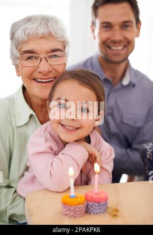 Gran fait les meilleurs petits gâteaux. Portrait d'une famille heureuse de trois générations célébrant un anniversaire à la maison. Banque D'Images