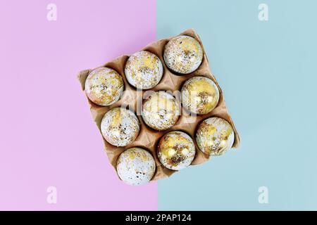 Peint les oeufs de Pâques avec des taches dorées dans la boîte à oeufs sur fond bleu et violet Banque D'Images