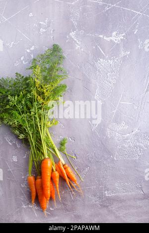 Bouquet de carottes fraîches avec des feuilles vertes sur fond de bois. Légumes. Banque D'Images