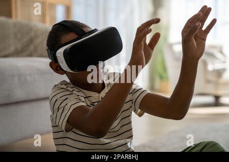 Petit garçon noir concentré toucher l'air avec les mains Explorer 3D lunettes de réalité virtuelle pour smartphone Banque D'Images