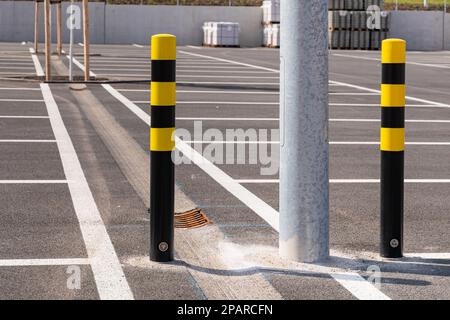 Bornes jaunes et noires dans le grand parking. Lignes pour les lotzs de stationnement dessinées sur l'asphalte. Banque D'Images