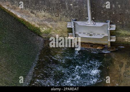 L'eau s'écoule à travers les vannes. Petit robinet-vanne métallique. Banque D'Images