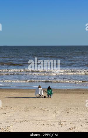 Galveston, Texas, États-Unis - février 2023 : deux personnes se détendent sur des chaises au bord de l'eau et donnent sur la mer Banque D'Images