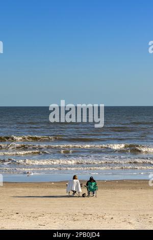 Galveston, Texas, États-Unis - février 2023 : deux personnes se détendent sur des chaises au bord de l'eau et donnent sur la mer Banque D'Images