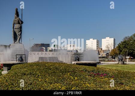 Guadalajara, Jalisco Mexique. 8 janvier 2023. Glorieta Minerva avec statue de la déesse romaine dans la fontaine entourée de buissons verts contre le bleu sk Banque D'Images