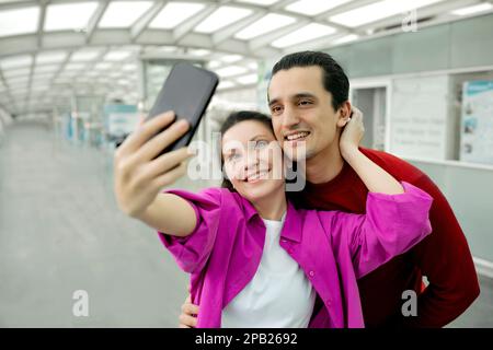 Couple de touristes heureux faisant Selfie sur téléphone mobile à l'aéroport Banque D'Images