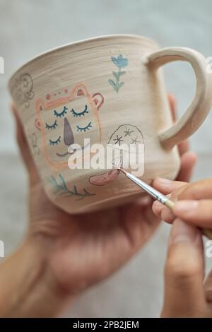 Gros plan d'une femme potter peignant une tasse dans son atelier d'artisanat. Banque D'Images
