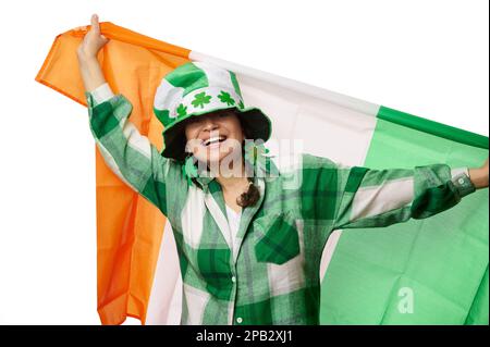 Jolie femme dans le chapeau de St Patrick et les feuilles de trèfle boucles d'oreilles, souriant, portant le drapeau de l'Irlande. Traditions culturelles irlandaises Banque D'Images