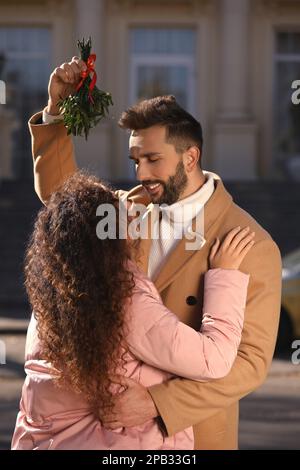 Couple heureux sous le groupe de GUI à l'extérieur. Tradition de Noël Banque D'Images