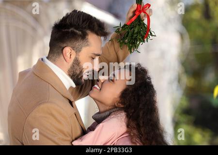 Couple heureux sous le groupe de GUI à l'extérieur. Tradition de Noël Banque D'Images