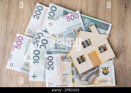 Prêt hypothécaire ou concept de prêt. De l'argent złoty polonais, des billets de zloty PLN et une maison modèle en bois. Acheter une maison, un appartement ou un appartement en Pologne. Banque D'Images