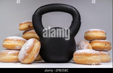 Kettlebell de gym et beignets polonais pączki frits. Un choix alimentaire sain pour les gras jeudi. Pączek fête en Pologne. Concept d'entraînement de perte de poids. Banque D'Images