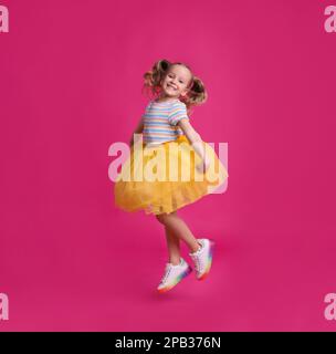 Mignon petit danseur en tutu jupe sautant sur fond rose Banque D'Images