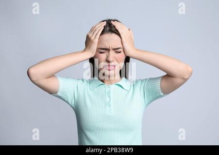 Jeune femme souffrant de maux de tête sur fond clair Banque D'Images