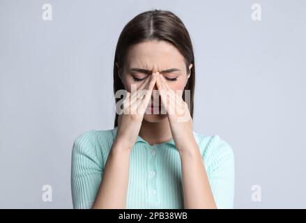 Jeune femme souffrant de maux de tête sur fond clair Banque D'Images