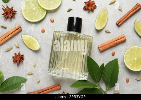 Composition de la couche plate avec bouteille de parfum, citron vert et épices sur fond gris clair Banque D'Images