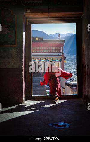 Un jeune moine traversant une porte au monastère de Thiksey, Ladakh, Inde Banque D'Images