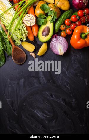 Légumes, herbes, ingrédients crus pour la cuisson et cuillère en bois sur fond rustique noir tableau de craie. Concept de saine alimentation propre. Végétalien ou gluten Banque D'Images