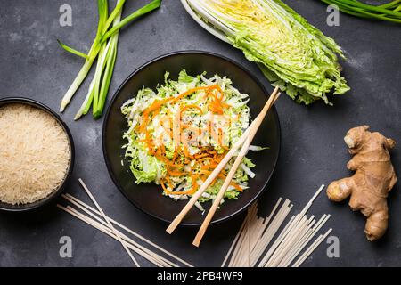 Salade asiatique ou chinoise au chou napa, carotte, graines de sésame noir. Ingrédients pour préparer le dîner chinois : nouilles de blé, riz, chou napa, gingembre Banque D'Images