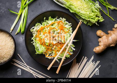 Salade asiatique ou chinoise au chou napa, carotte, graines de sésame noir. Ingrédients pour préparer le dîner chinois : nouilles de blé, riz, chou napa, gingembre Banque D'Images