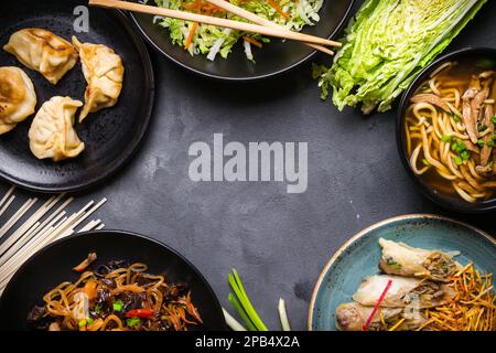 Cuisine chinoise fond sombre. Nouilles chinoises, riz frit, soupe de nouilles, dim sum, rouleaux de printemps, salade. Plats de cuisine chinoise traditionnelle. Espace pour Banque D'Images