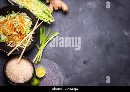 Ingrédients pour la cuisine du dîner vietnamien : papier de riz, riz, chou napa, gingembre, oignon vert, salade. Ingrédients de cuisine asiatique. Vue de dessus. Faire la vie Banque D'Images