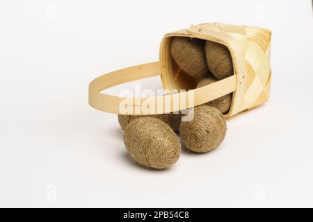 Composition de Pâques. Panier avec œufs enveloppés dans une ficelle de jute. Arrière-plan blanc. Studio Banque D'Images