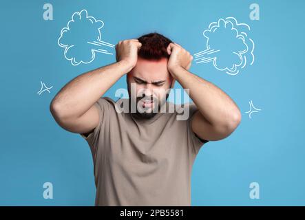 Jeune homme ayant des maux de tête sur fond bleu clair. Illustration de la vapeur représentant une douleur sévère Banque D'Images