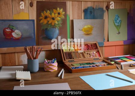 Feuilles de papier vierges, pastels craie colorés et crayons à dessin sur table en bois à l'intérieur. Le lieu de travail de l'artiste moderne Banque D'Images