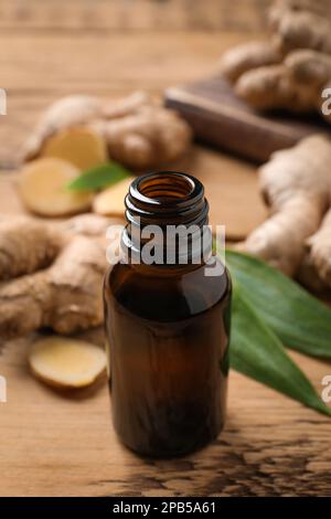 Bouteille en verre d'huile essentielle et racine de gingembre sur table en bois Banque D'Images