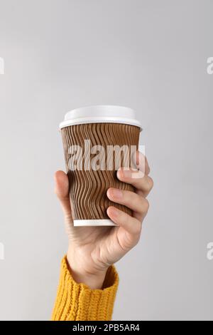 Femme tenant une tasse à café en papier à emporter sur fond blanc, gros plan Banque D'Images